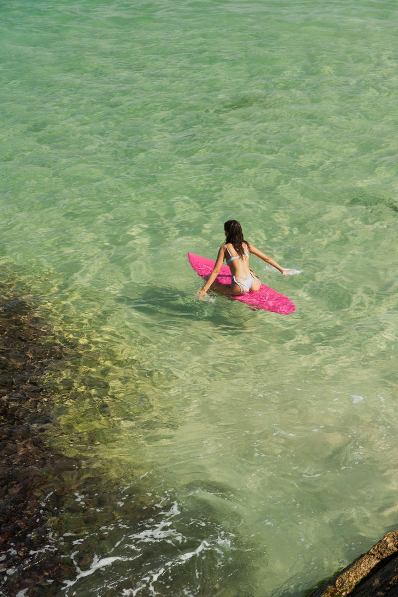 mulher dentro da agua do mar em cima de prancha