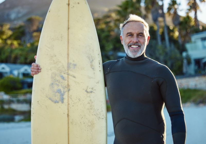 homem segurando um prancha e sorrindo