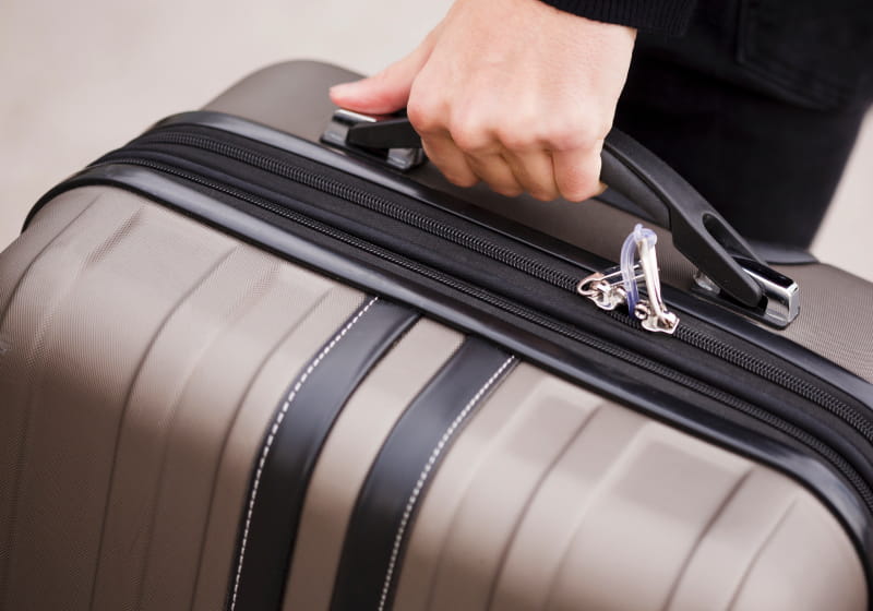 homem segurando mala de viajem 