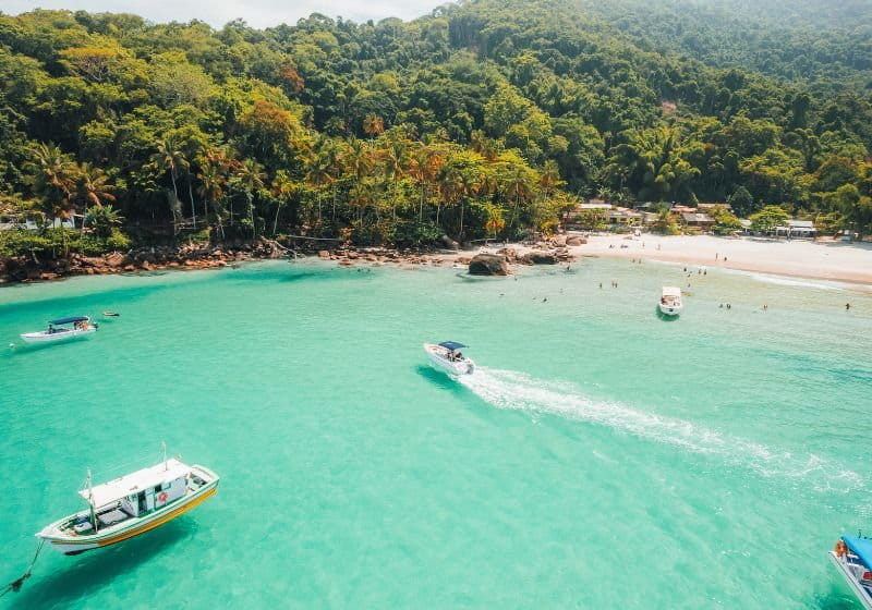 Praia de Aventureiro, em Ilha Grande na agua com vários barcos e pessoa na areia