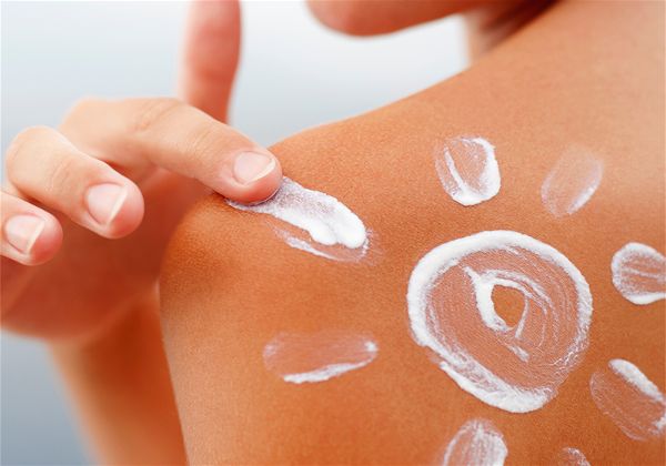 mulher virada de costas, mostrando o ombro com sol desenhado de protetor solar