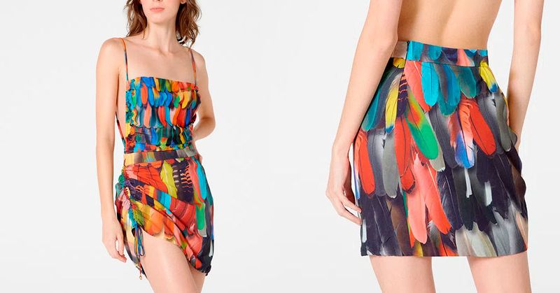 Modelo vestindo uma saia mini com estampa colorida de penas em um fundo branco