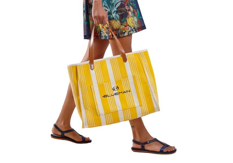 Mulher utilizando bolsa de praia amarela com listras brancas