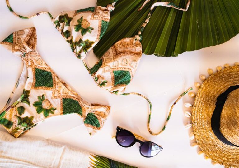 Imagem com biquíni, chapéu de palha e óculos em cima de pano branco