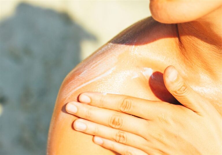 Mulher passando protetor solar no ombro