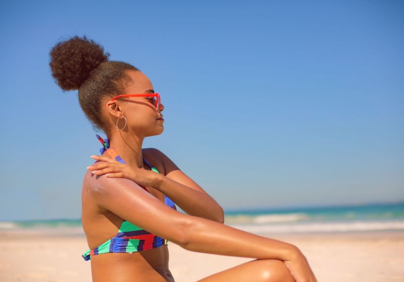 mulher sentada a beira mar usando um coque.