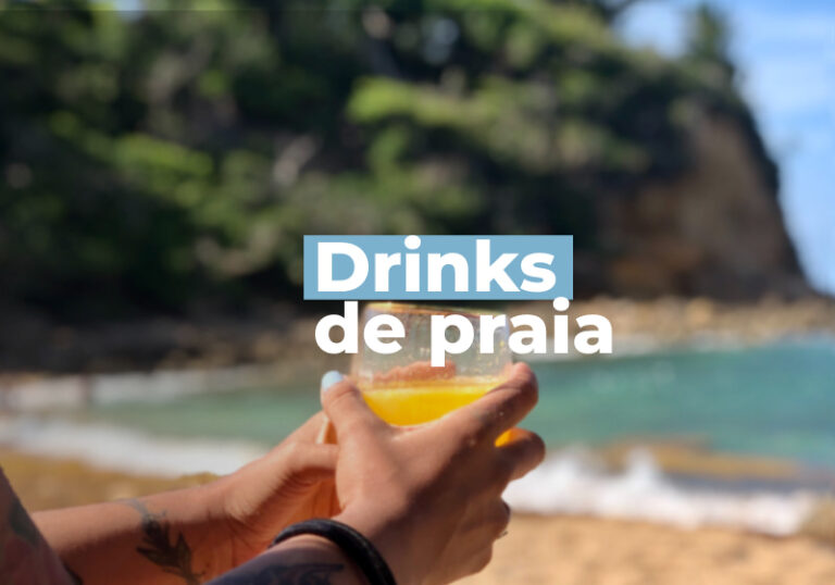 foto de mao segurando copo com drink e praia ao fundo