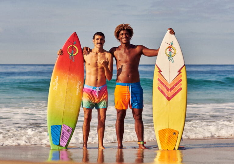 dois amigos surfista na beira da praia segurando suas prancha em pé