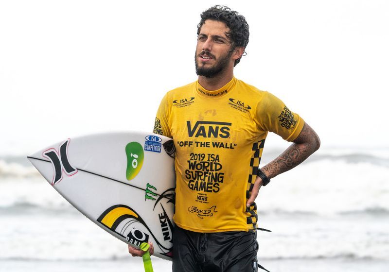 surfista felipe toledo segurando prancha e mar ao fundo