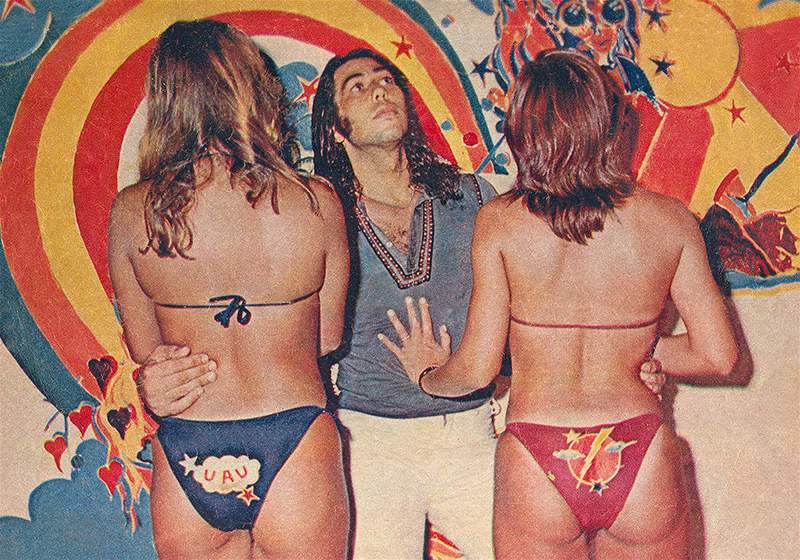 Duas mulheres vestidas biquíni de costas e no meio David Azulay