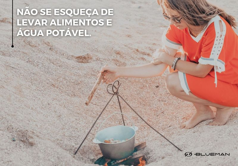 Mulher cozinhando alimentos em fogueira na praia.