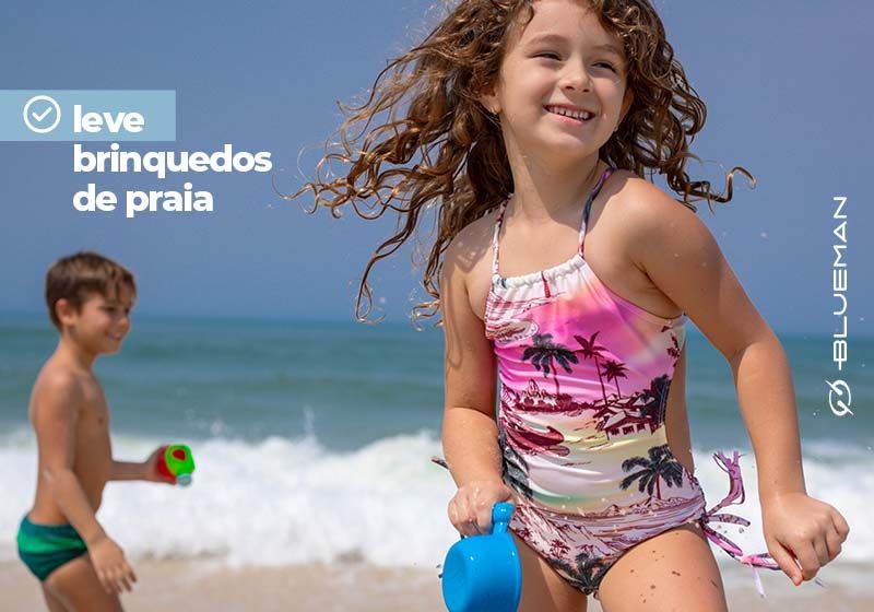 Menino e menina brincando na beira da praia com brinquedos.