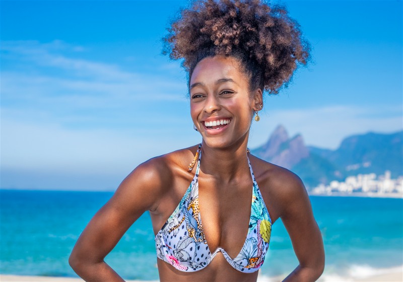 Mulher sorridente com na cintura vestindo biquíni estampado