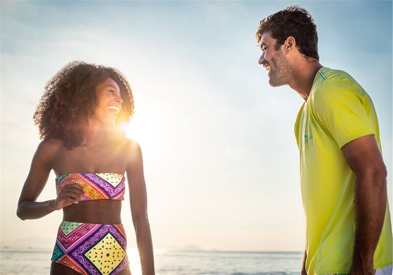 Homem e mulher em praia sorriendentes, em dia ensolarado