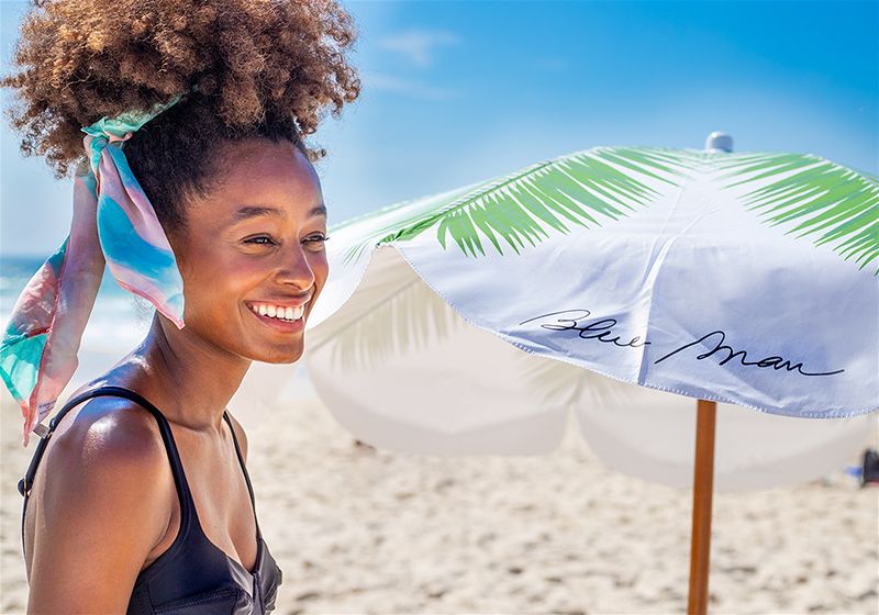 Mulher sorridente em praia, utilizando biquíni preto