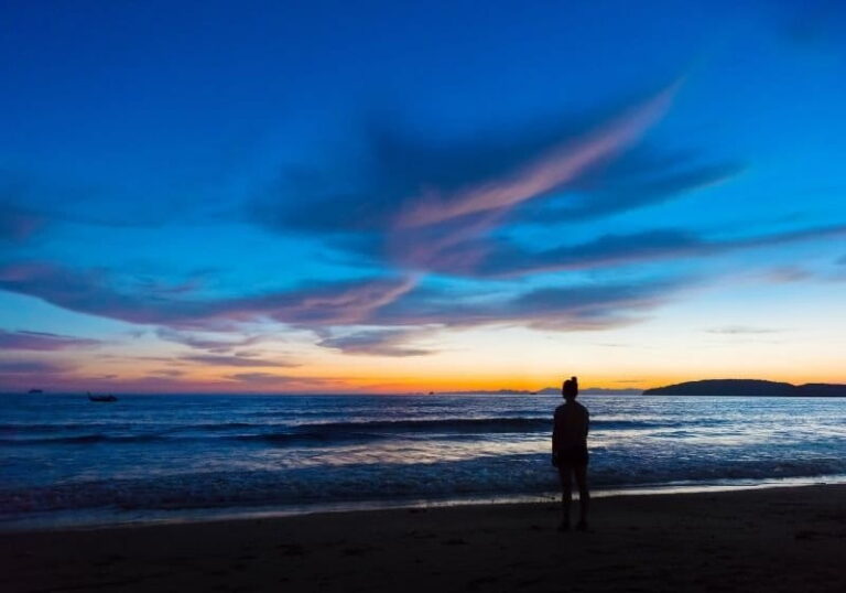 mulher de frente pra praia ao amanhecer