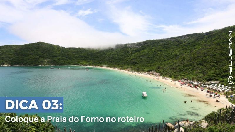 Inclua a Praia do Forno no roteiro Vista aérea de praia envolvida por montanhas verdes.