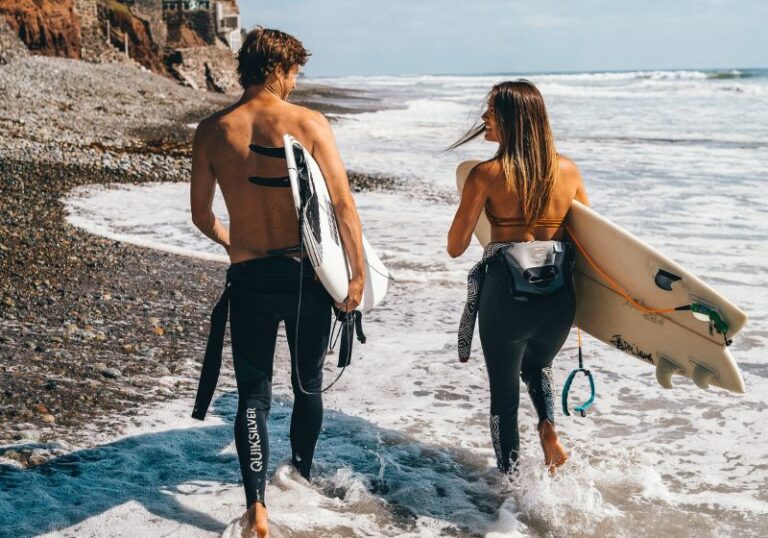 dois surfistas lado a lado de costas e mar ao fundo