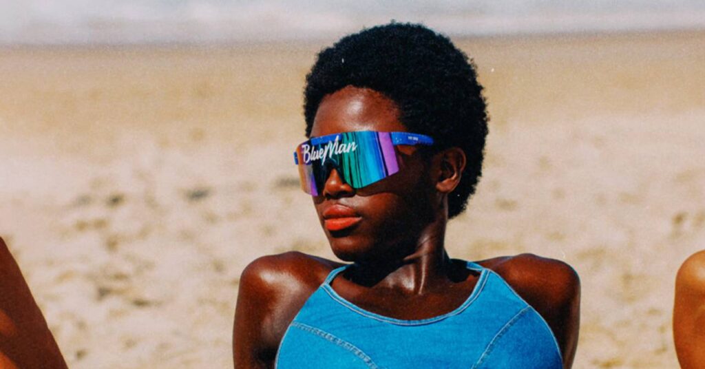 Mulher com óculos de sol da blueman tomando sol na praia