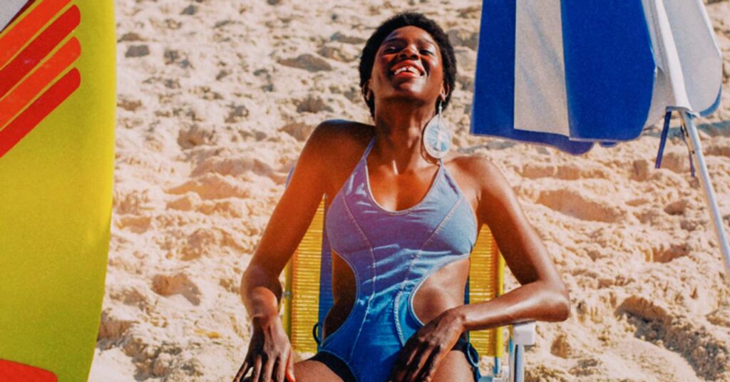 Mulher feliz tomando sol e sentada na cadeira de praia