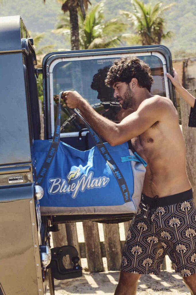 Homem tirando uma mala azul de dentro do carro